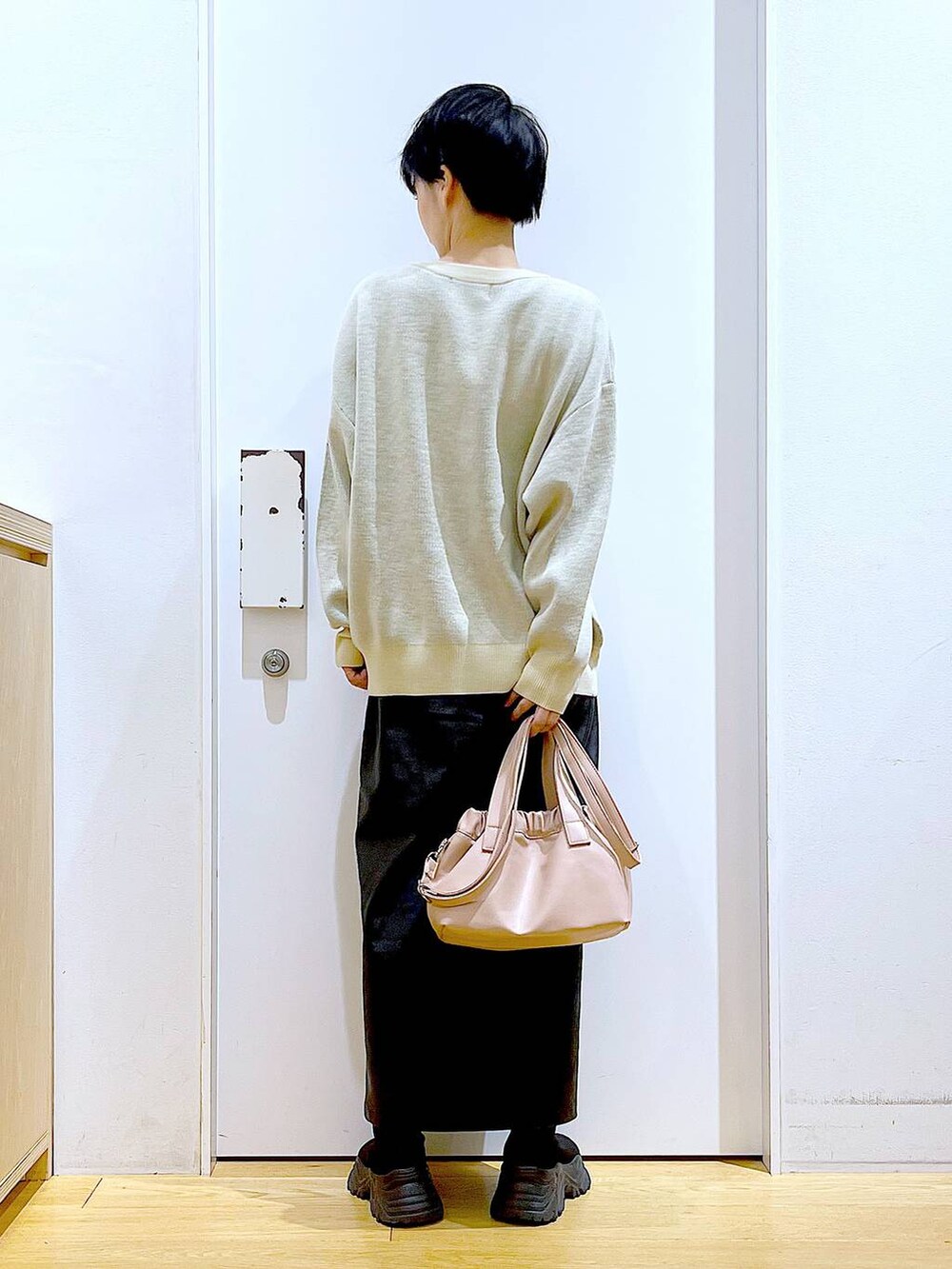 ブラック系のスカート、ブラック系のブーツ、ピンク系のショルダーバッグを着用したレディースの冬コーディネートの5枚目の写真