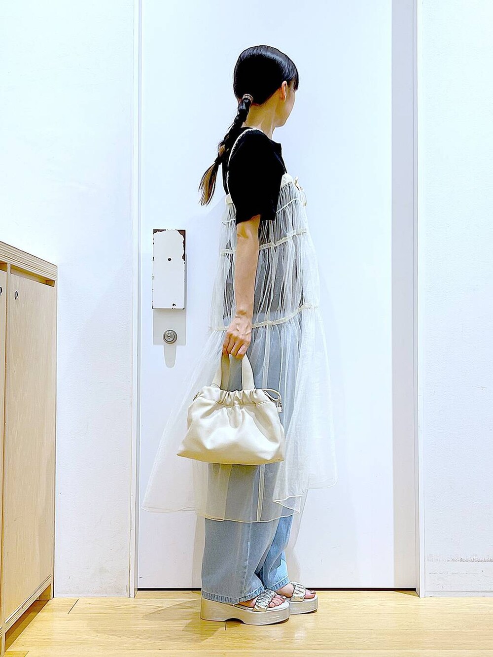 ブルー系のデニムパンツ、ホワイト系のショルダーバッグ、ブラック系のTシャツ/カットソーを着用したレディースの夏コーディネートの4枚目の写真