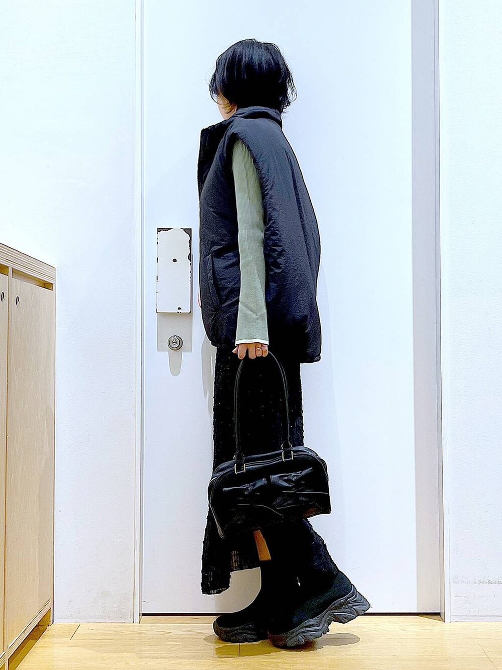 グリーン系のニット/セーター、ブラック系のハンドバッグ、ブラック系のブーツを着用したレディースの秋コーディネートの3枚目の写真