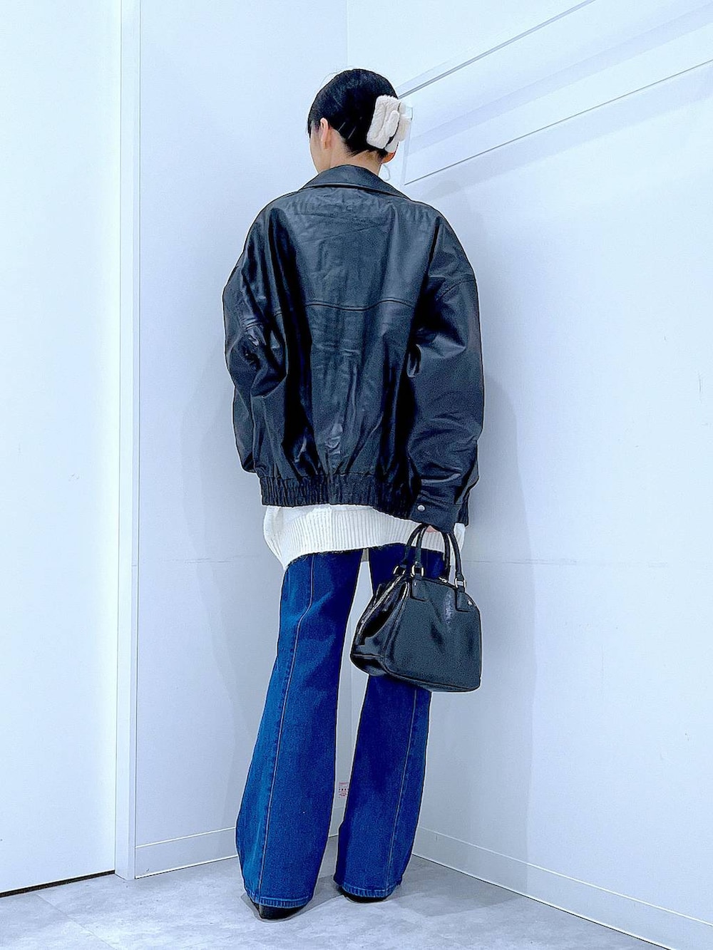 ブラック系のブルゾン、ブラック系のブーツ、ブラック系のショルダーバッグを着用したレディースの冬コーディネートの5枚目の写真