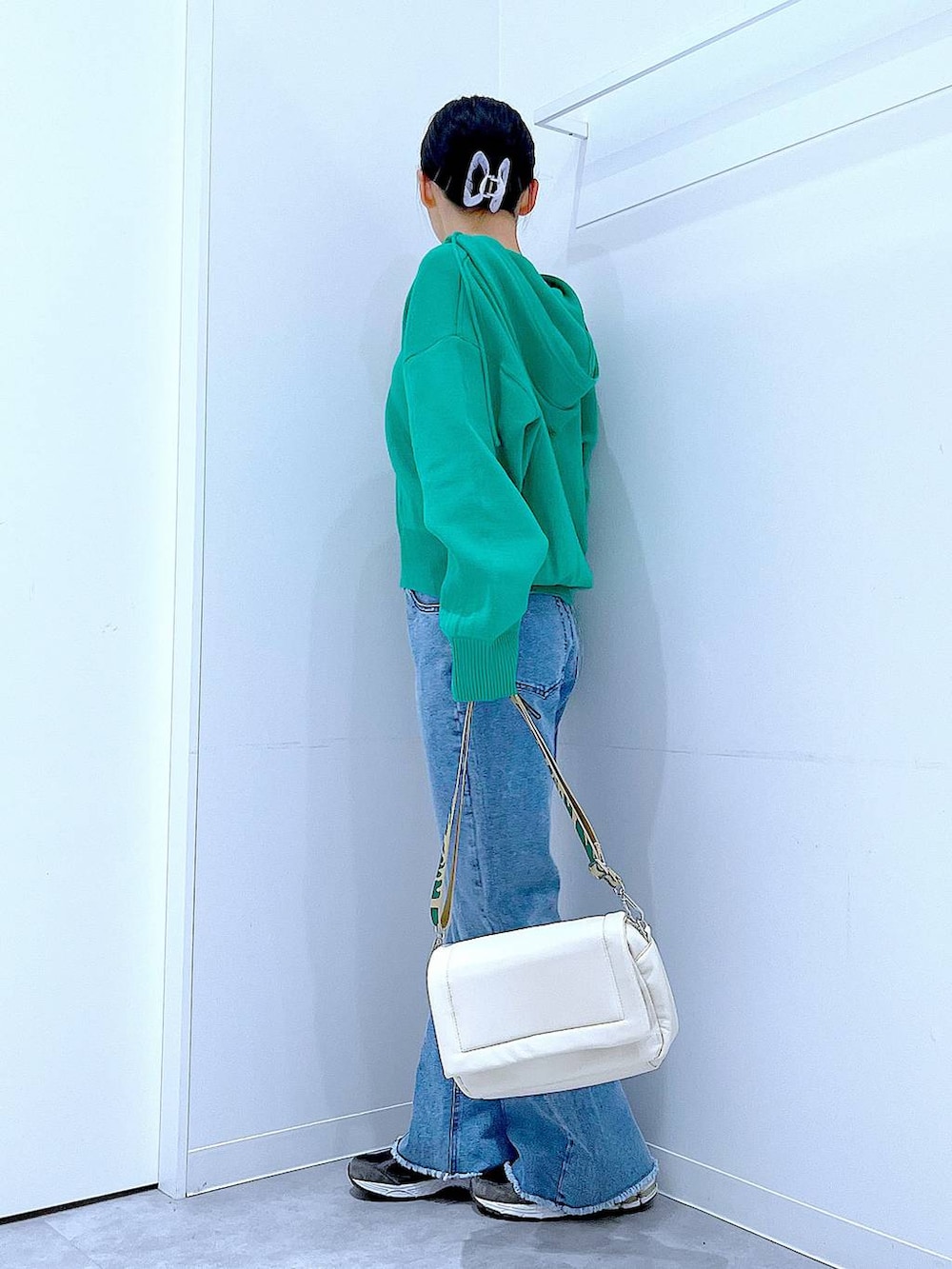 ホワイト系のショルダーバッグ、グリーン系のニット/セーター、ブルー系のデニムパンツを着用したレディースの春コーディネートの3枚目の写真