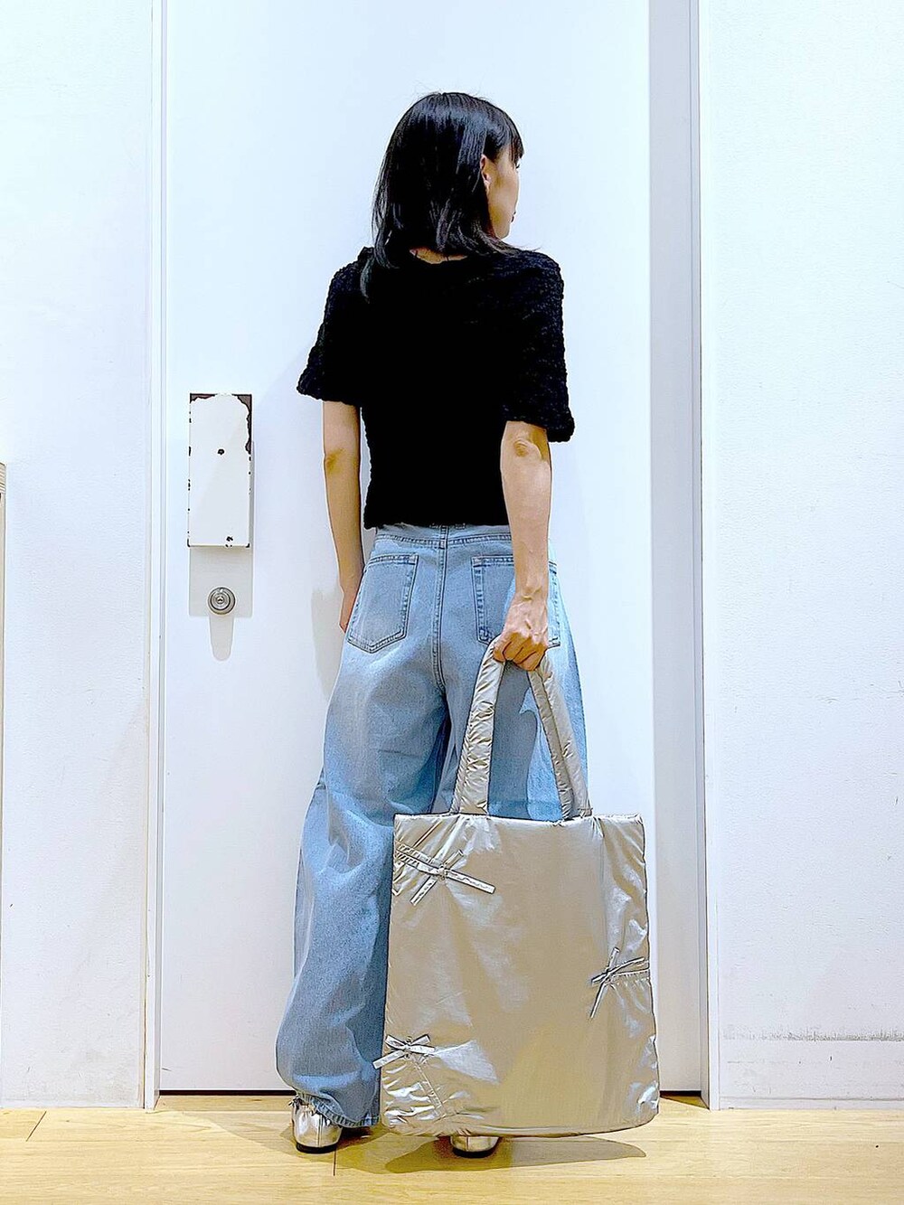 ブラック系のカーディガン/ボレロ、シルバー系のトートバッグ、ブルー系のデニムパンツを着用したレディースの秋コーディネートの5枚目の写真