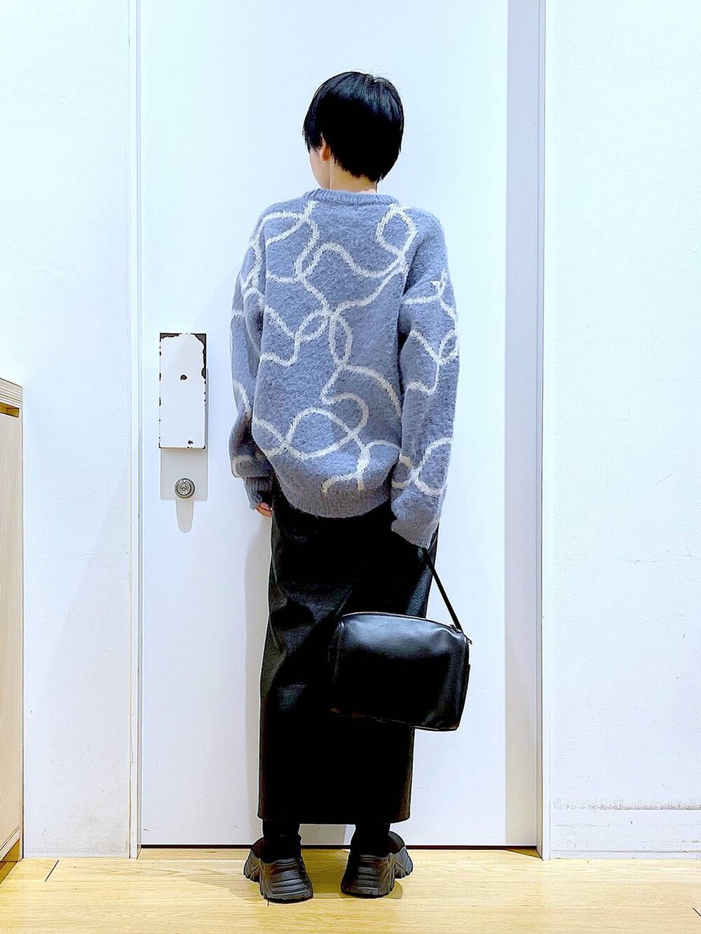 ブラック系のスカート、ブラック系のショルダーバッグ、ブラック系のブーツを着用したレディースの冬コーディネートの5枚目の写真