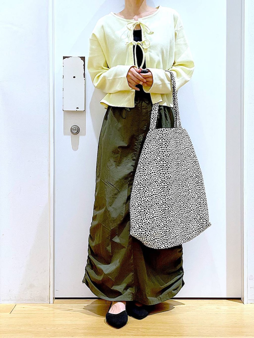 イエロー系のカーディガン/ボレロ、グリーン系のスカート、ベージュ系のトートバッグを着用したレディースの春コーディネートの6枚目の写真