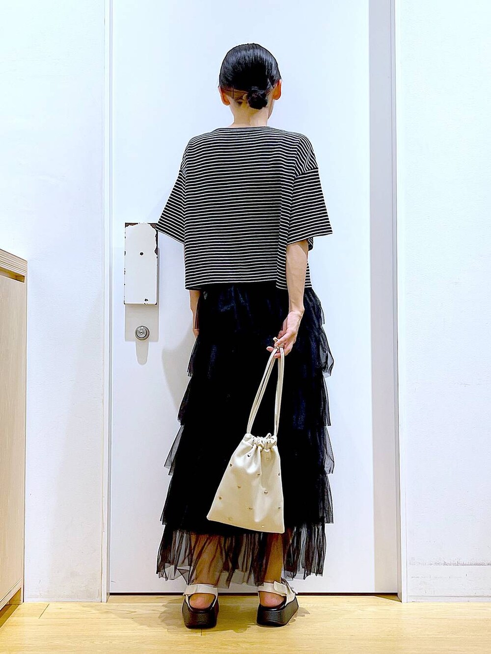 ホワイト系のサンダル、ホワイト系のショルダーバッグ、ブラック系のスカートを着用したレディースの夏コーディネートの5枚目の写真