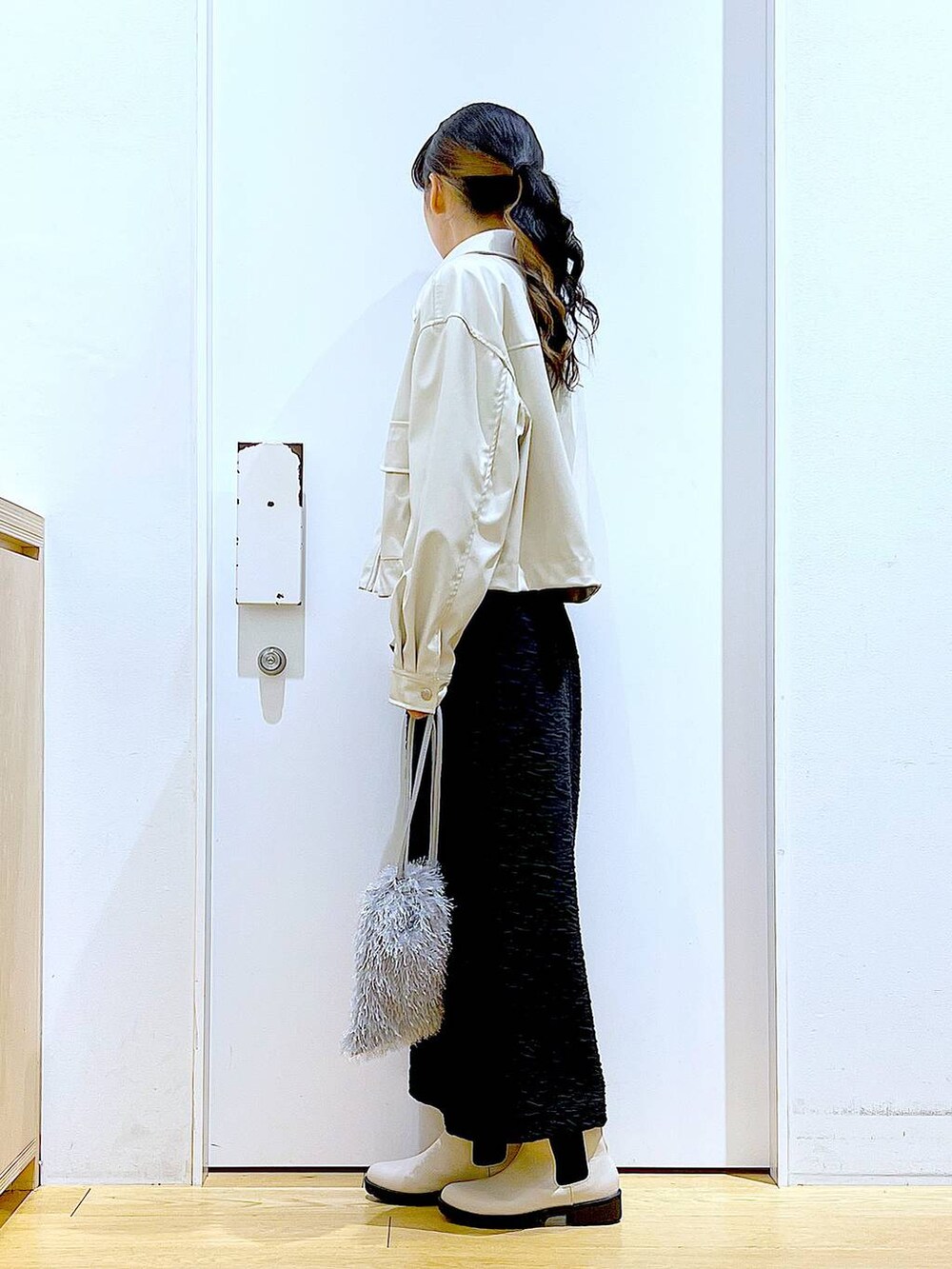 ブラック系のスカート、ベージュ系のブルゾン、ベージュ系のブーツを着用したレディースの春コーディネートの3枚目の写真