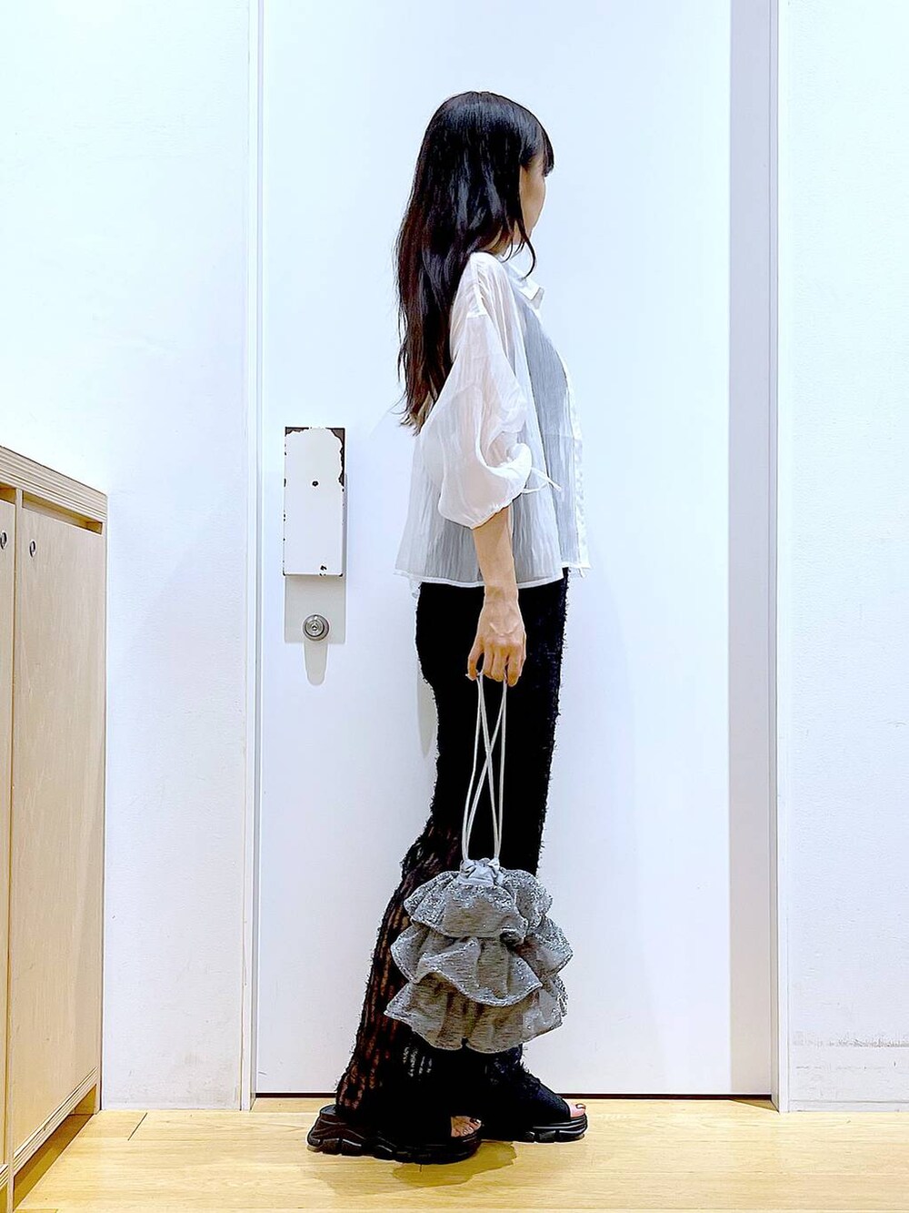 シルバー系のショルダーバッグ、ブラック系のニット/セーター、ブラック系のサンダルを着用したレディースの夏コーディネートの4枚目の写真