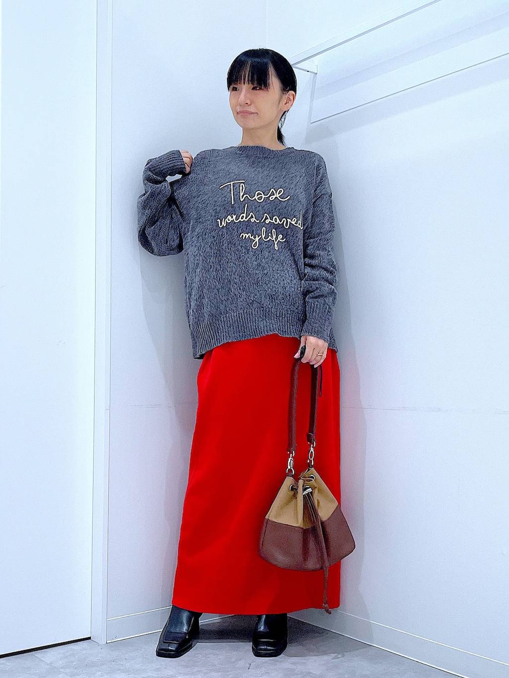 ベージュ系のショルダーバッグ、ブラック系のブーツ、グレー系のニット/セーターを着用したレディースの冬コーディネートの2枚目の写真