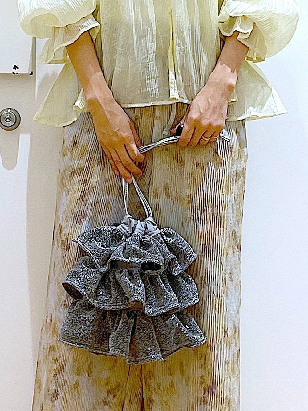 シルバー系のショルダーバッグ、シルバー系のパンプス、ベージュ系のシャツ/ブラウスを着用したレディースの夏コーディネートの9枚目の写真