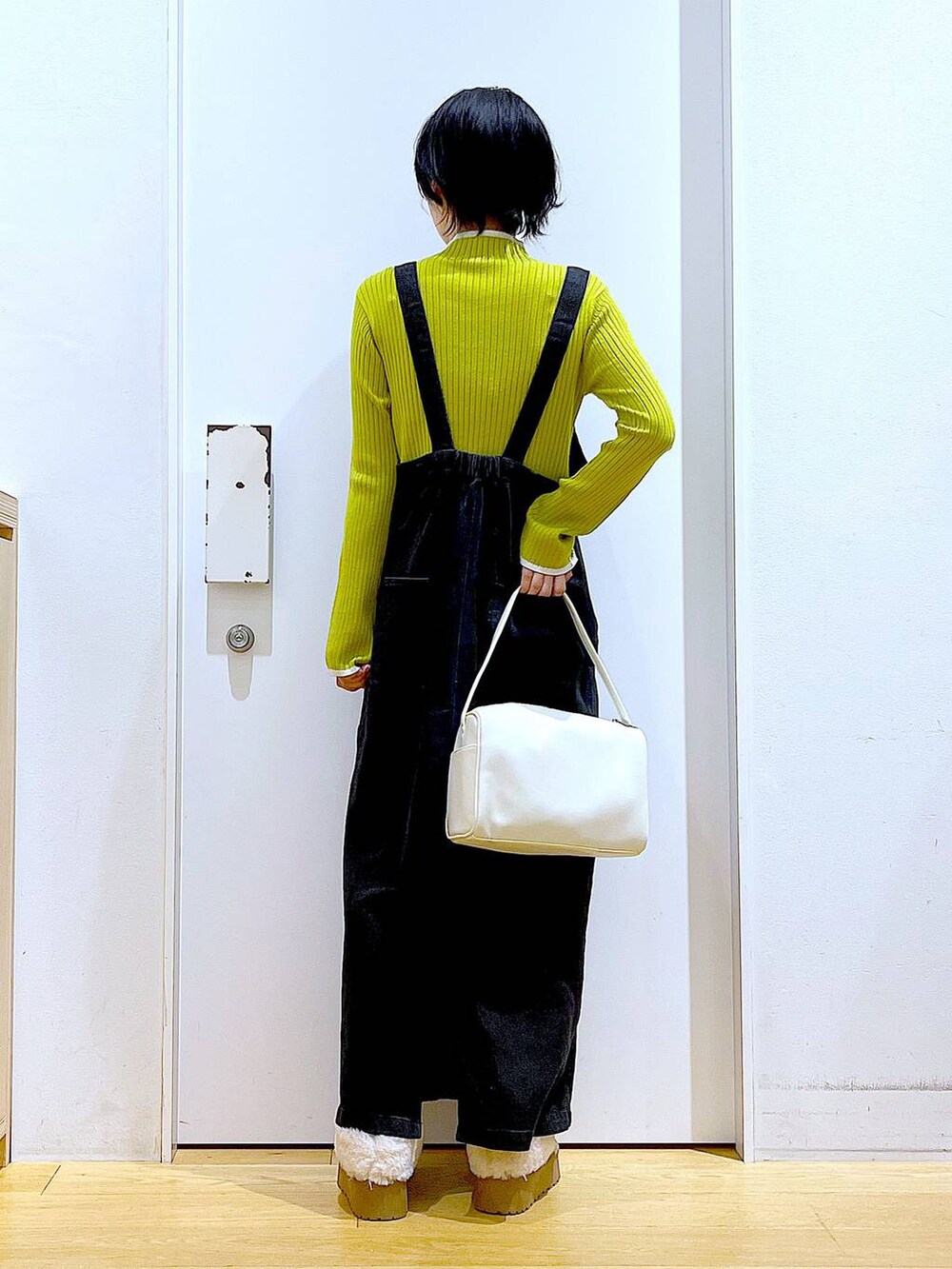 グレー系のジャンパースカート、ホワイト系のショルダーバッグ、グリーン系のニット/セーターを着用したレディースの冬コーディネートの5枚目の写真