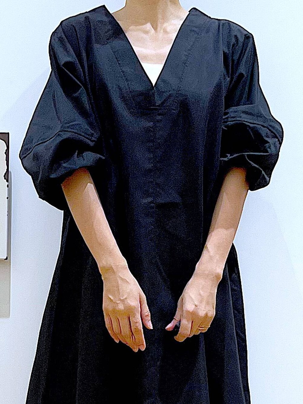 イエロー系のハンドバッグ、ブラック系のワンピース、ブラック系のパンプスを着用したレディースの秋コーディネートの7枚目の写真