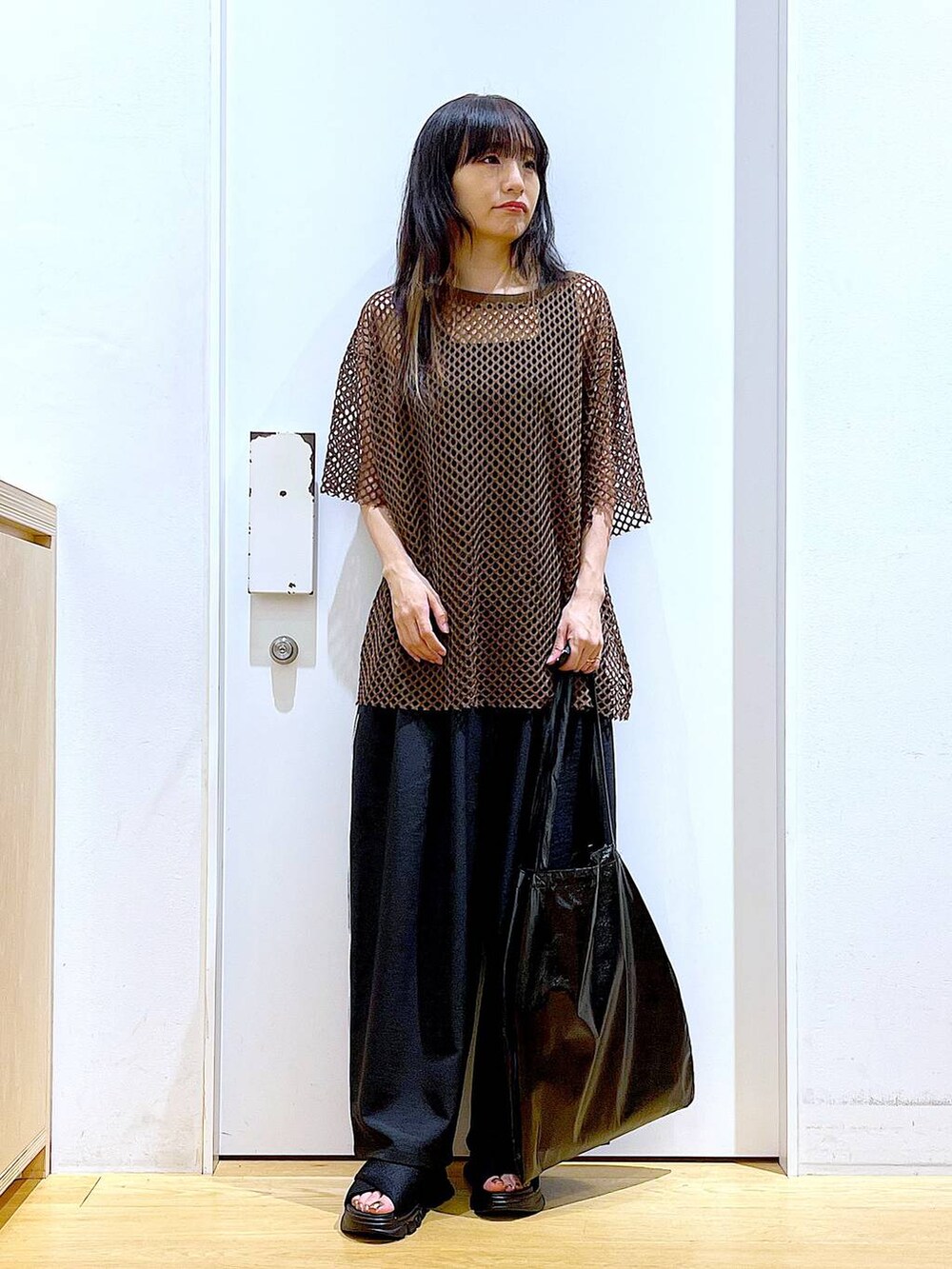 ブラック系のトートバッグ、ブラック系のニット/セーター、ブラック系のサンダルを着用したレディースの夏コーディネートの2枚目の写真