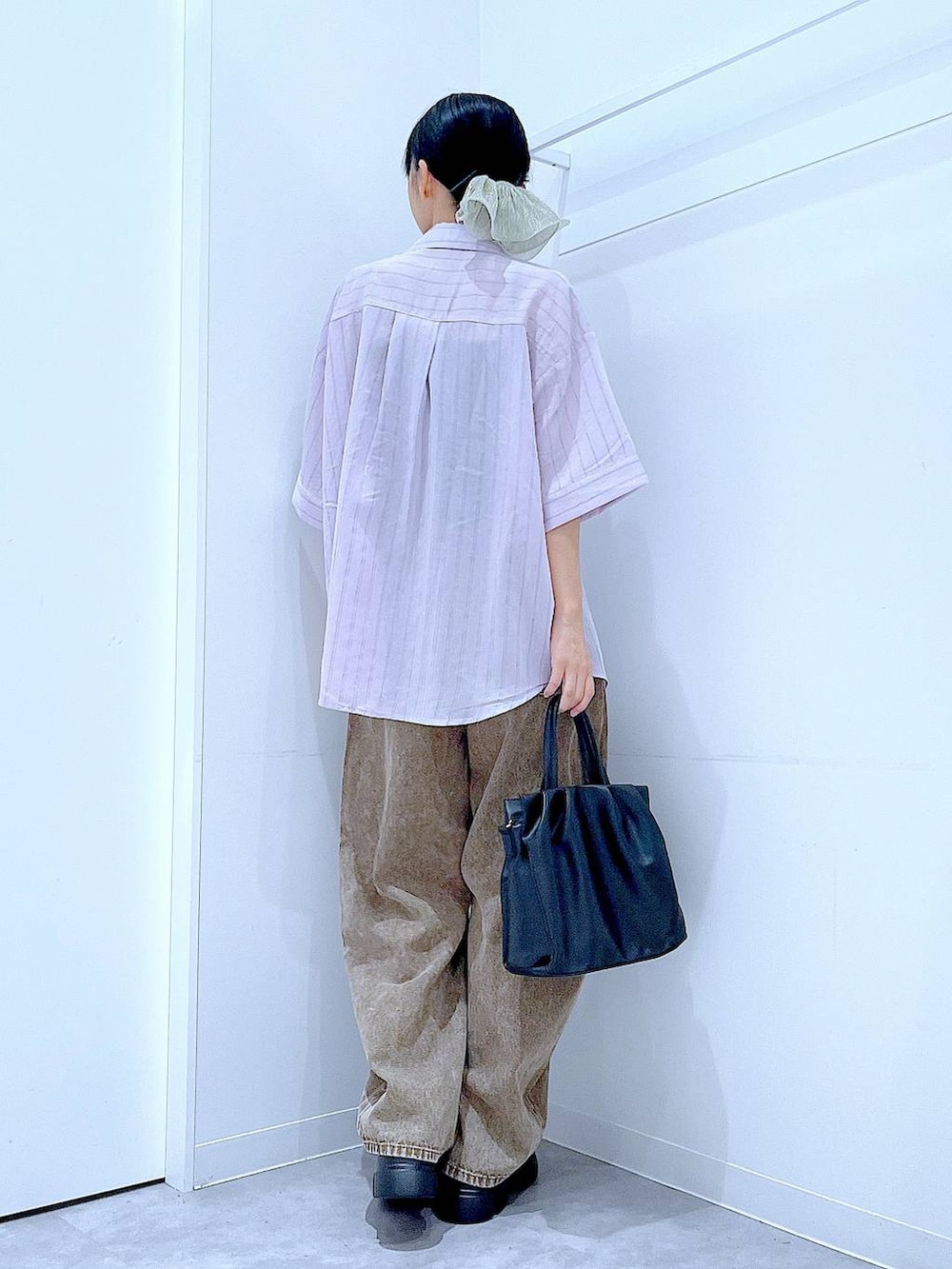 ブラウン系のデニムパンツ、ブラック系のサンダル、ブラック系のハンドバッグを着用したレディースの夏コーディネートの5枚目の写真