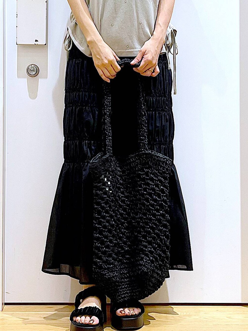 ブラック系のサンダル、ブラック系のスカート、ブラック系のトートバッグを着用したレディースの夏コーディネートの9枚目の写真