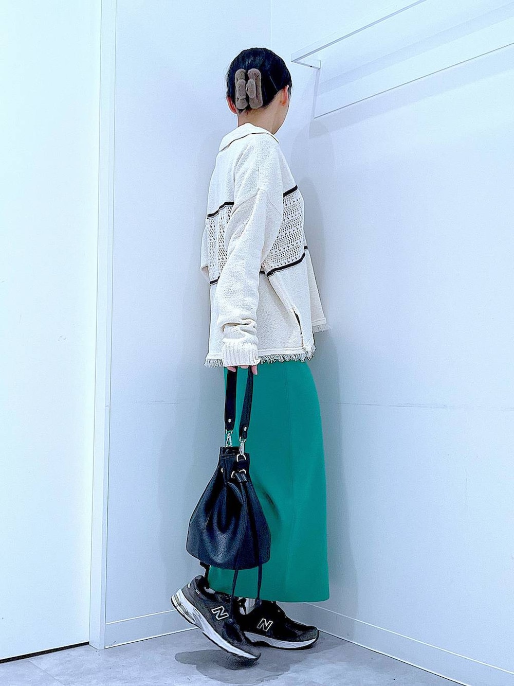 ブラック系のTシャツ/カットソー、グリーン系のスカート、ホワイト系のニット/セーターを着用したレディースの冬コーディネートの4枚目の写真