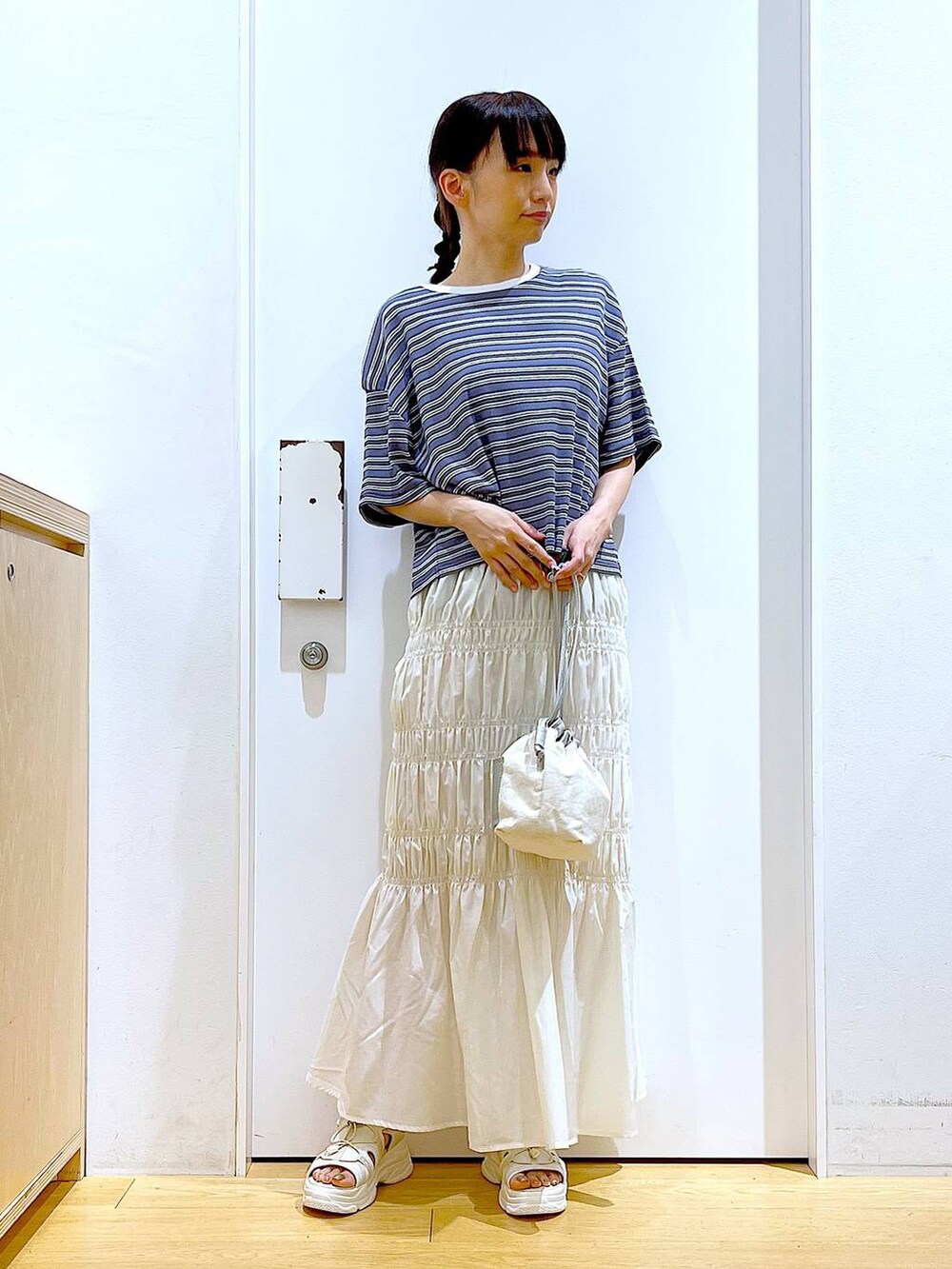 ホワイト系のショルダーバッグ、ホワイト系のサンダル、グレー系のTシャツ/カットソーを着用したレディースの夏コーディネートの2枚目の写真