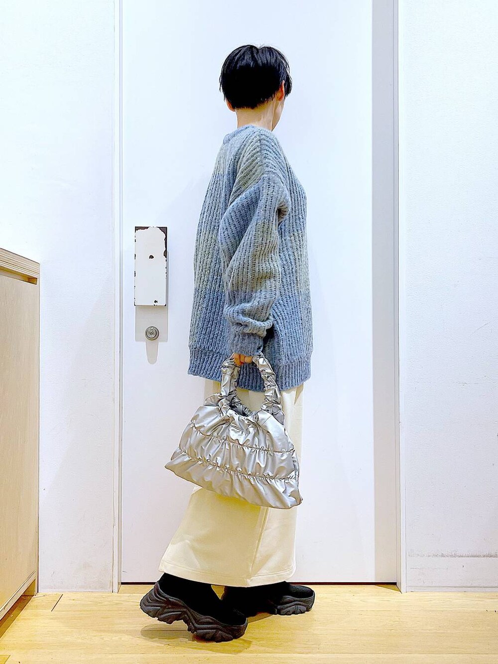 ブルー系のニット/セーター、ブラック系のブーツ、シルバー系のショルダーバッグを着用したレディースの冬コーディネートの4枚目の写真