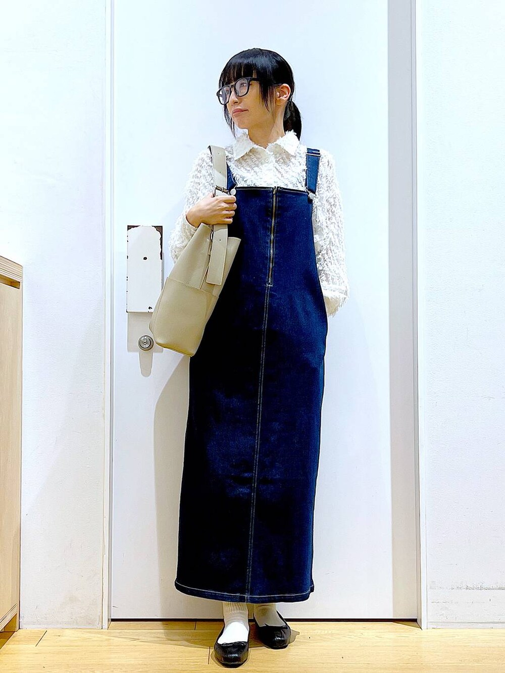 グレー系のショルダーバッグ、ブラック系のバレエシューズ、ブルー系のジャンパースカートを着用したレディースの春コーディネートの2枚目の写真