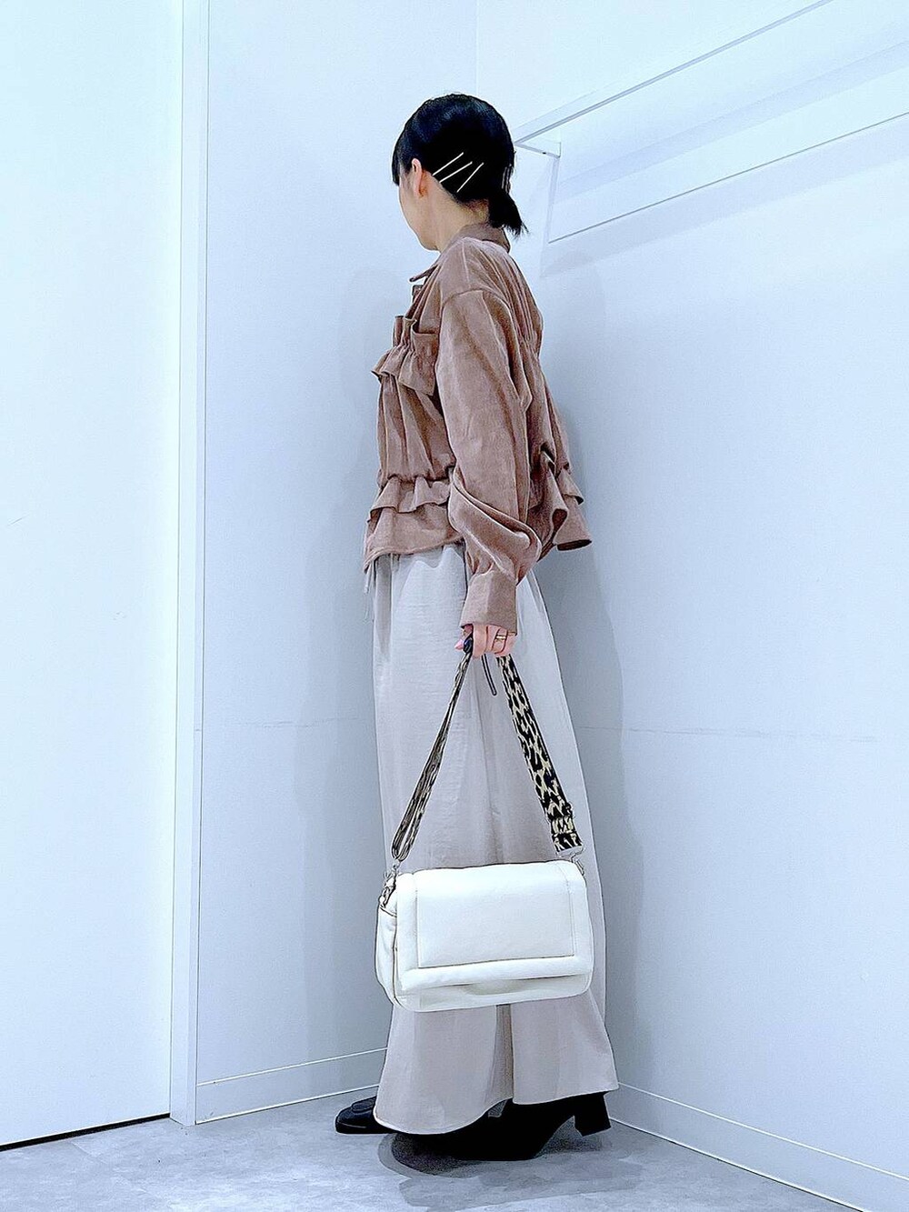 ベージュ系のスカート、ホワイト系のショルダーバッグ、ブラック系のブーツを着用したレディースの秋コーディネートの3枚目の写真