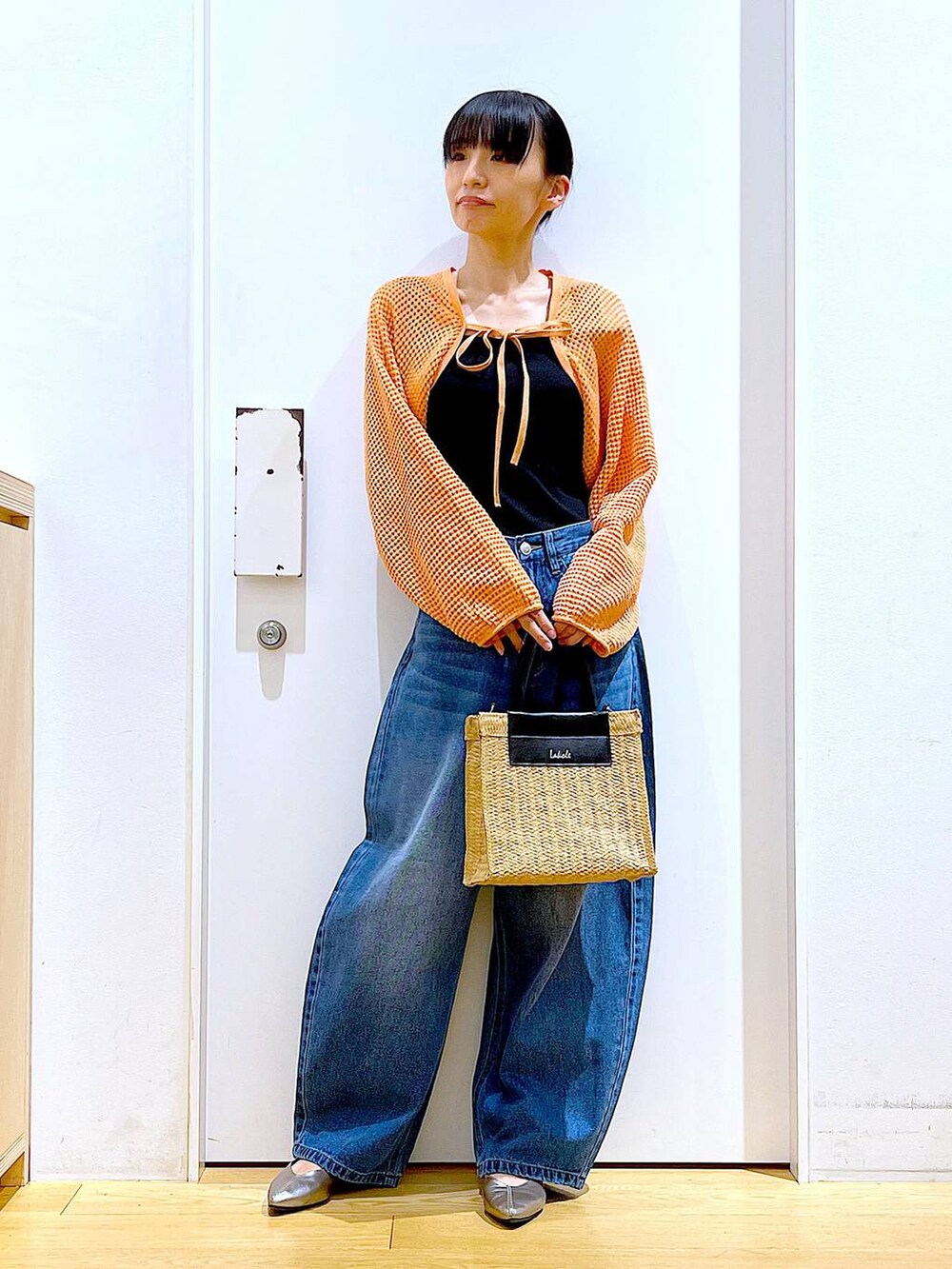 ブルー系のデニムパンツ、オレンジ系のカーディガン/ボレロ、その他のパンプスを着用したレディースの春コーディネートの2枚目の写真