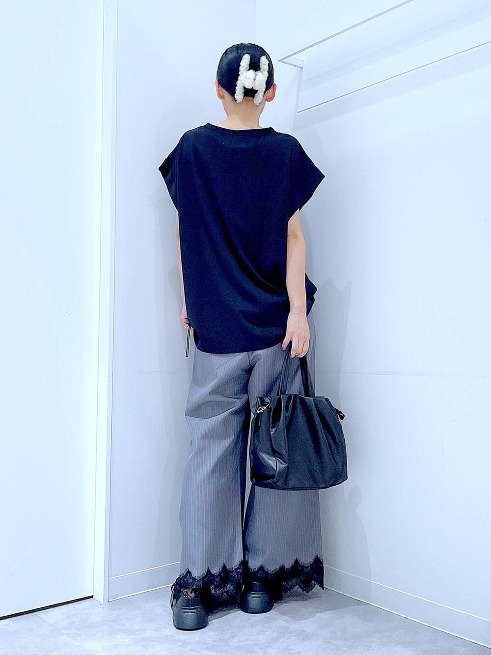 ブラック系のTシャツ/カットソー、グレー系のスラックス、ブラック系のハンドバッグを着用したレディースの秋コーディネートの5枚目の写真