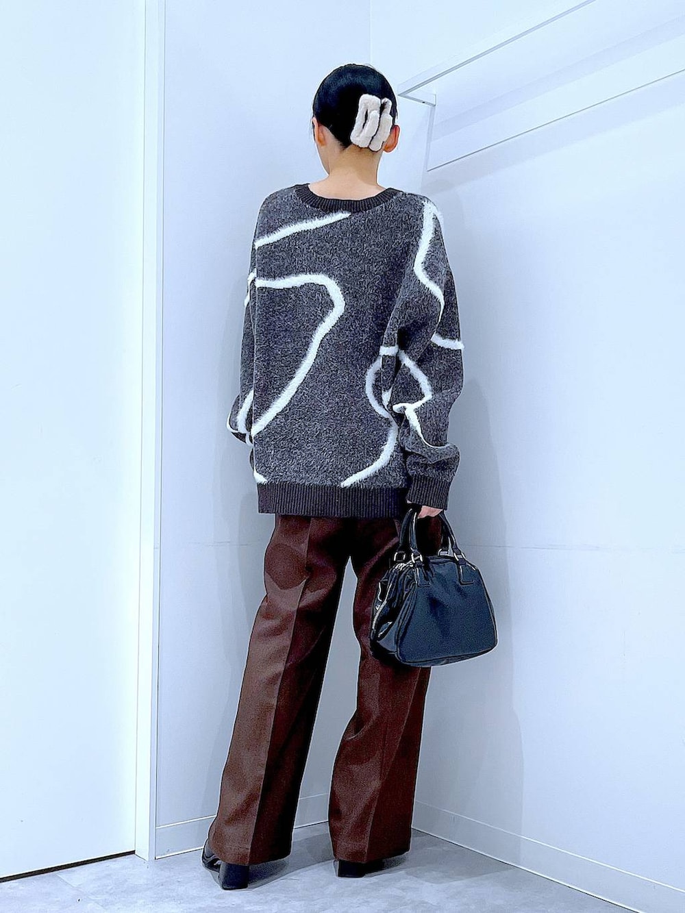 ブラック系のブーツ、ブラウン系のスラックス、ブラック系のショルダーバッグを着用したレディースの冬コーディネートの5枚目の写真