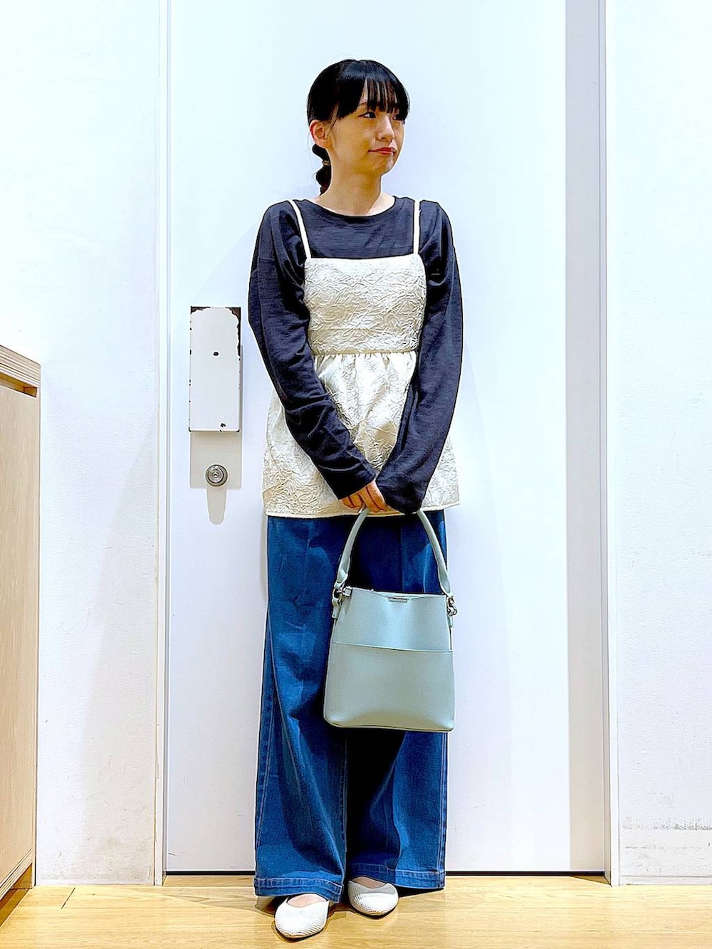 ブルー系のデニムパンツ、ホワイト系のキャミソール、グリーン系のショルダーバッグを着用したレディースの春コーディネートの2枚目の写真