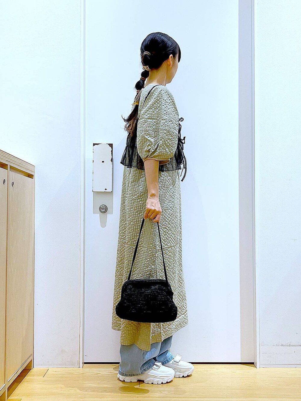 ホワイト系のスニーカー、ブルー系のデニムパンツ、ブラック系のショルダーバッグを着用したレディースの春コーディネートの4枚目の写真