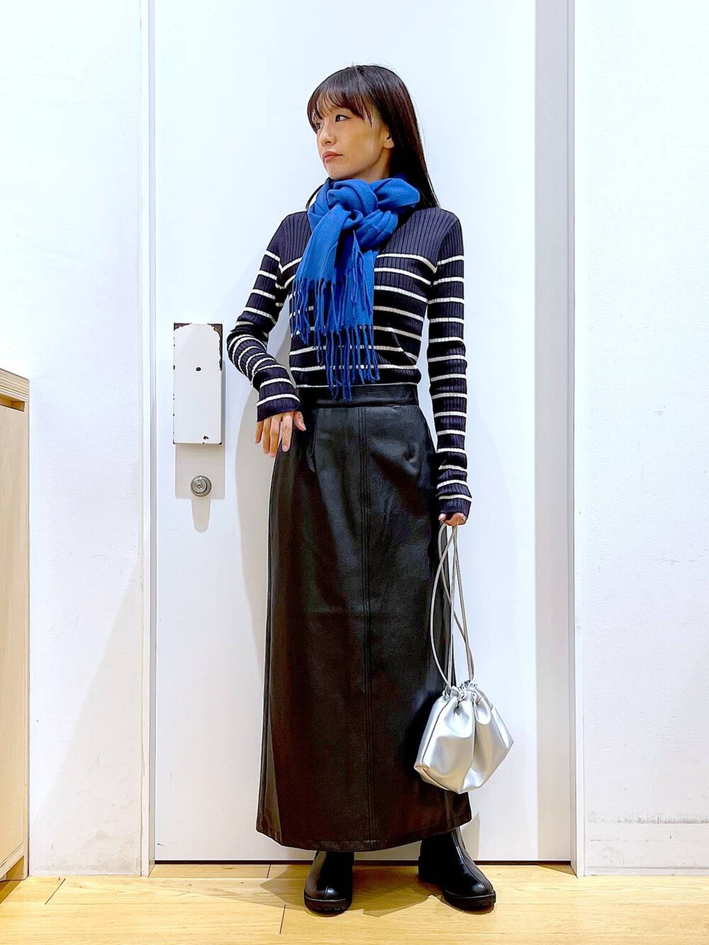 ブラック系のブーツ、ブルー系のニット/セーター、シルバー系のショルダーバッグを着用したレディースの冬コーディネートの2枚目の写真