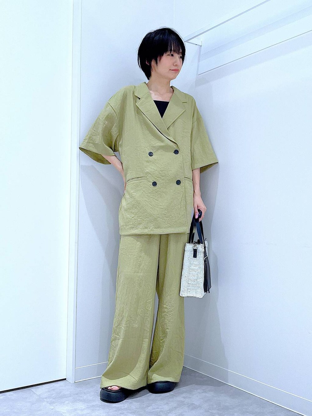 ホワイト系のショルダーバッグ、ブラック系のサンダル、グリーン系のテーラードジャケットを着用したレディースの夏コーディネートの2枚目の写真