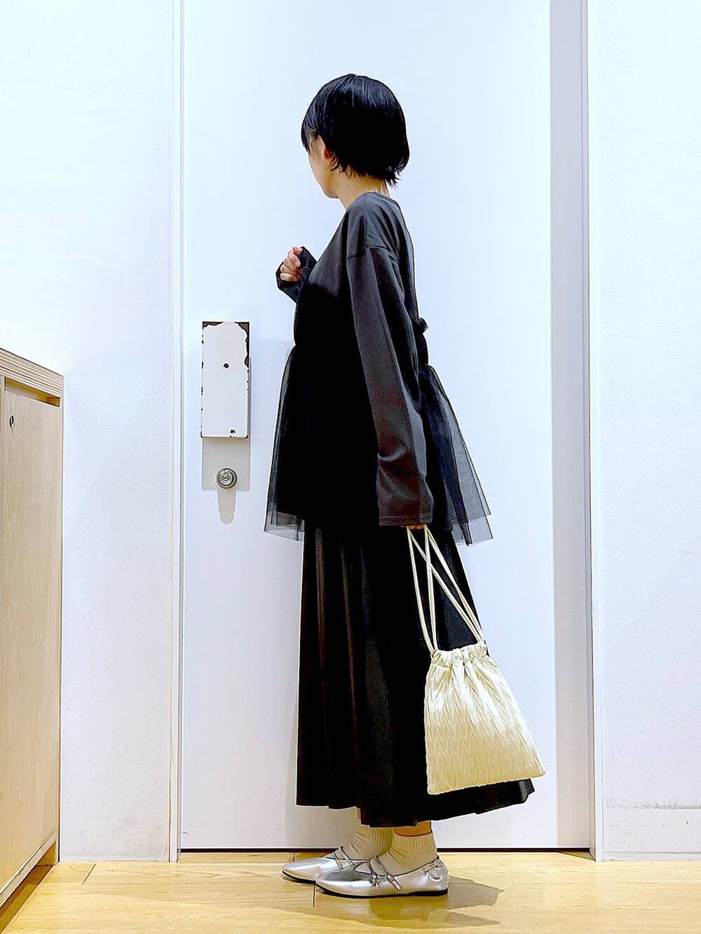 ホワイト系のショルダーバッグ、シルバー系のパンプス、ブラック系のスカートを着用したレディースの秋コーディネートの3枚目の写真