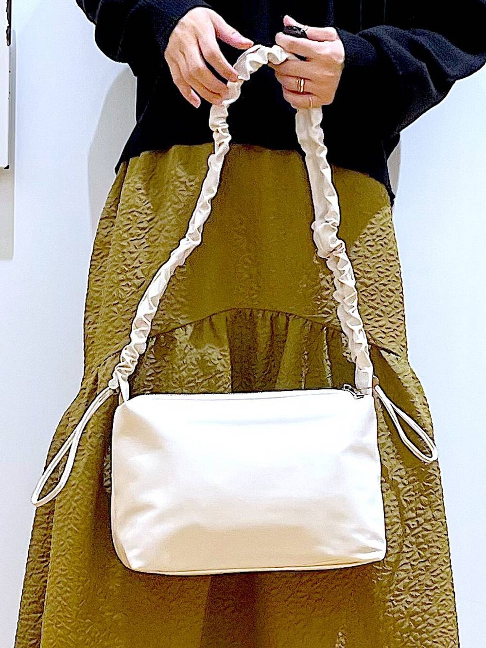 ホワイト系のショルダーバッグ、ベージュ系のブーツ、ブラック系のニット/セーターを着用したレディースの冬コーディネートの2枚目の写真