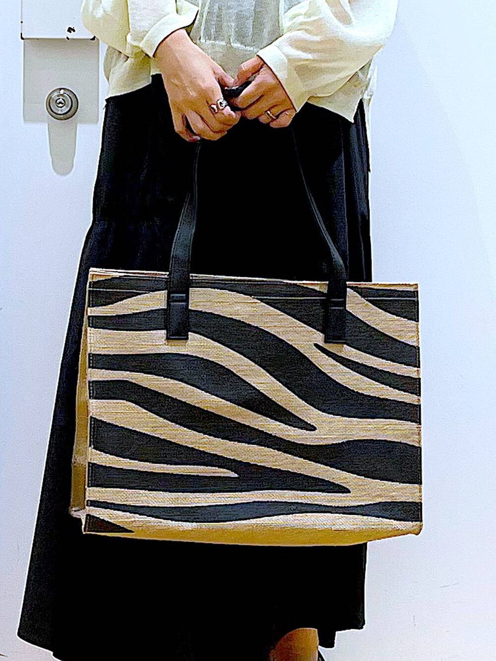 ホワイト系のニット/セーター、ブラック系のスカート、ブラック系のパンプスを着用したレディースの夏コーディネートの9枚目の写真