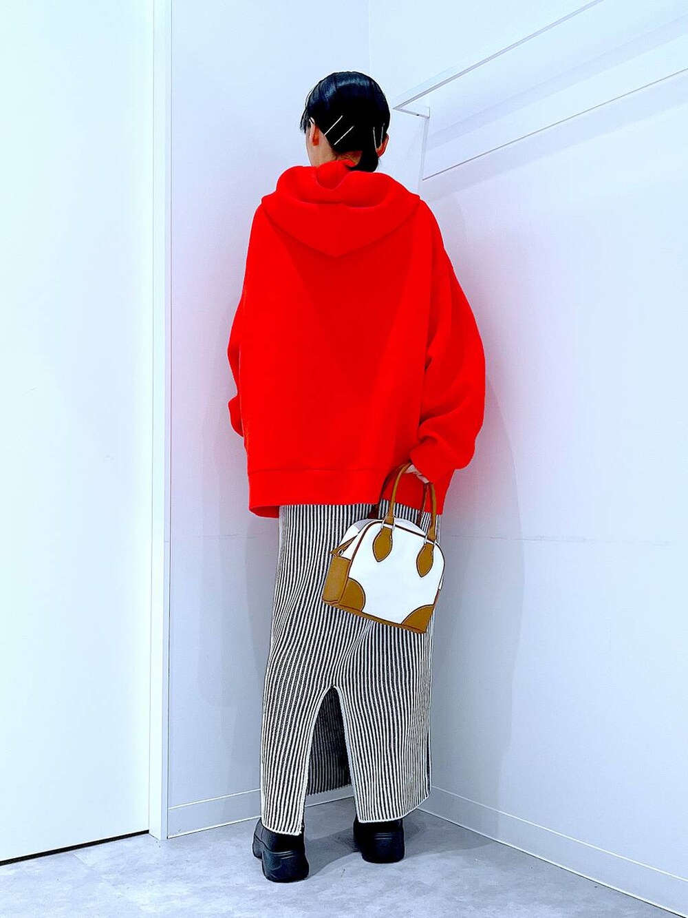 ブラック系のブーツ、ベージュ系のスカート、ホワイト系のハンドバッグを着用したレディースの秋コーディネートの5枚目の写真