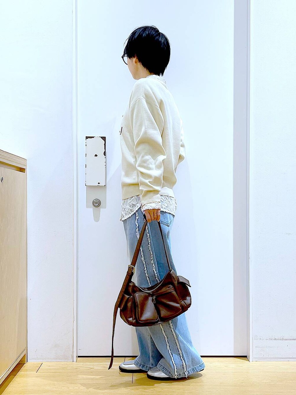 シルバー系のローファー、ブラウン系のショルダーバッグ、ホワイト系のニット/セーターを着用したレディースの春コーディネートの3枚目の写真