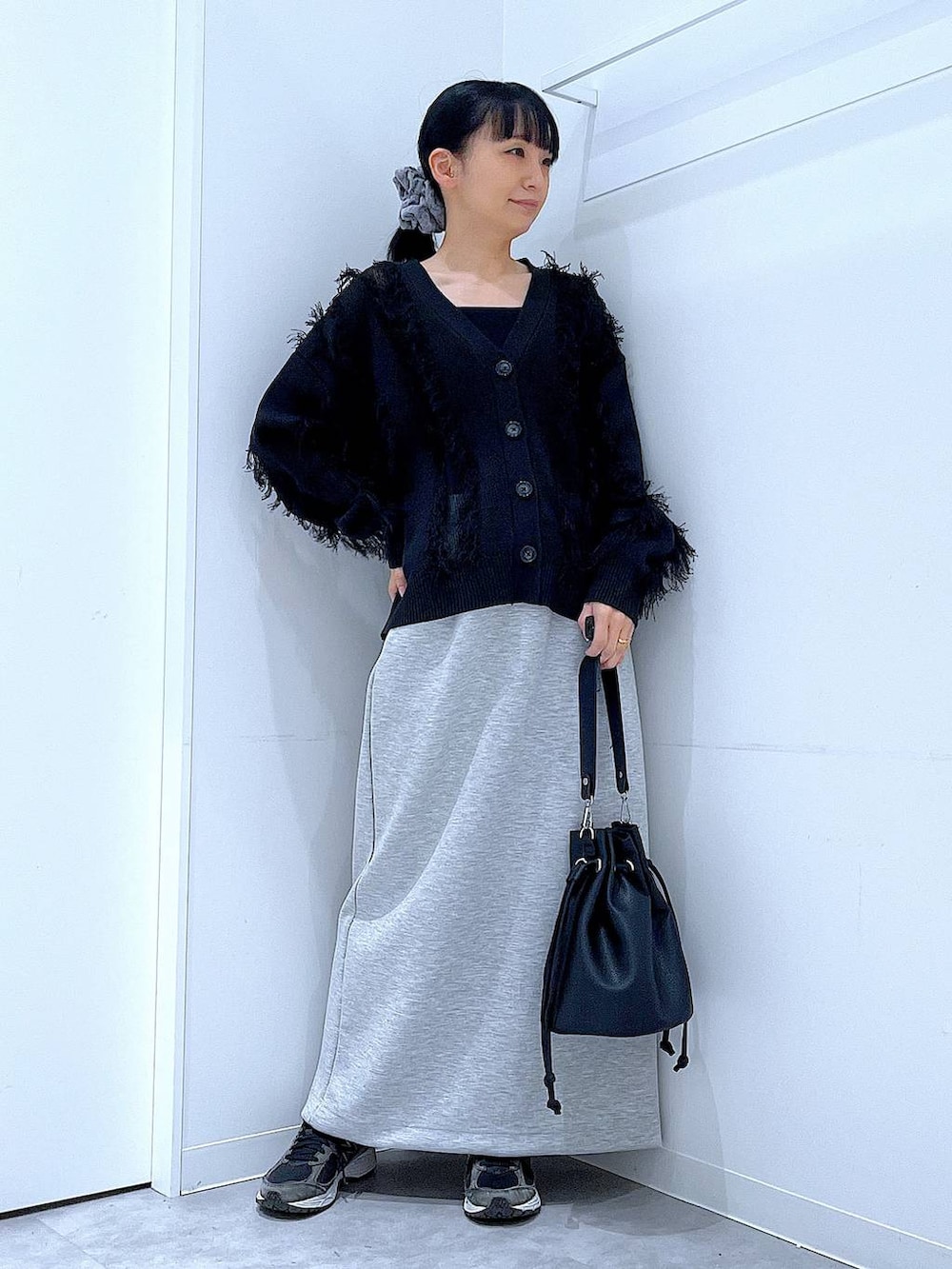 グレー系のスカート、ブラック系のショルダーバッグ、ブラック系のカーディガン/ボレロを着用したレディースの春コーディネートの2枚目の写真