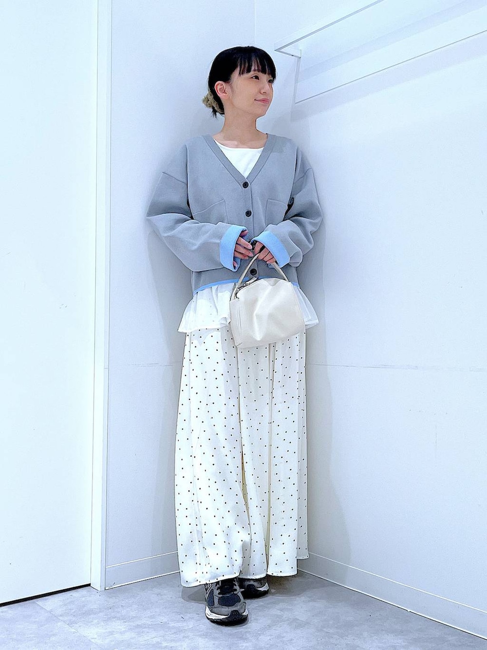 ホワイト系のショルダーバッグ、グレー系のカーディガン/ボレロ、ホワイト系のスカートを着用したレディースの春コーディネートの2枚目の写真