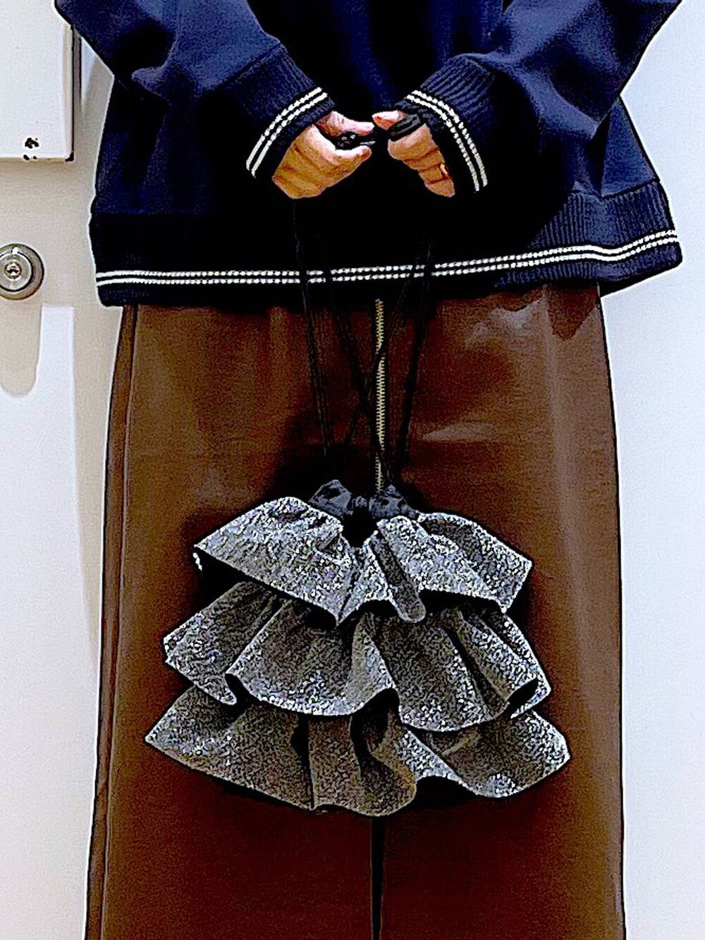 ブラウン系のスカート、ブラック系のブーツ、シルバー系のショルダーバッグを着用したレディースの冬コーディネートの9枚目の写真