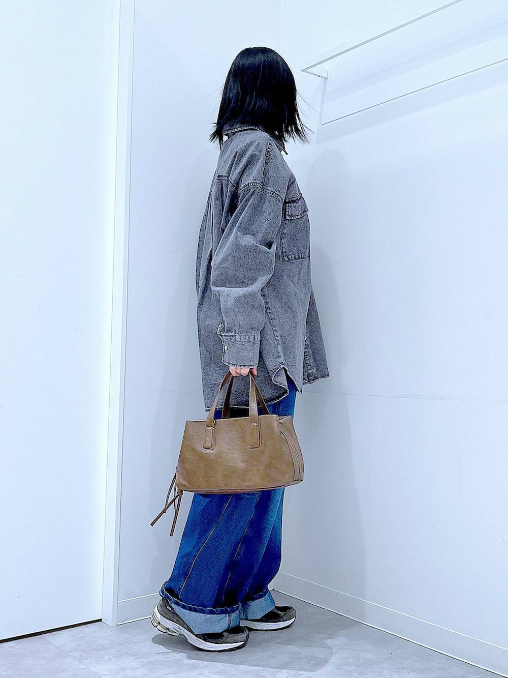 ブラウン系のボストンバッグ、ブルー系のデニムパンツ、ブラック系のシャツ/ブラウスを着用したレディースの冬コーディネートの4枚目の写真