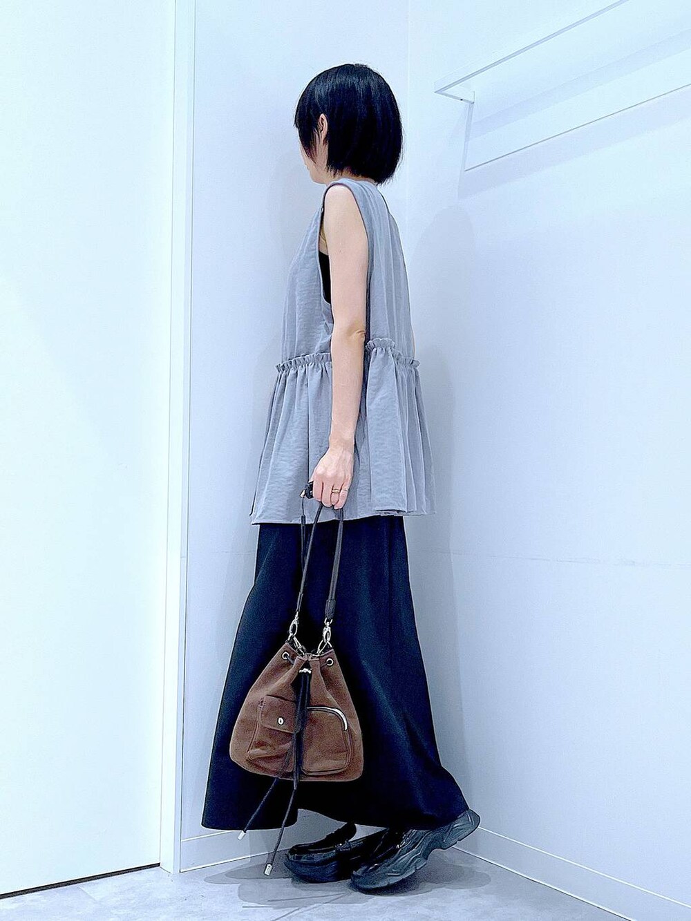 ブラック系のスカート、ブラック系のローファー、ブラウン系のショルダーバッグを着用したレディースの秋コーディネートの3枚目の写真