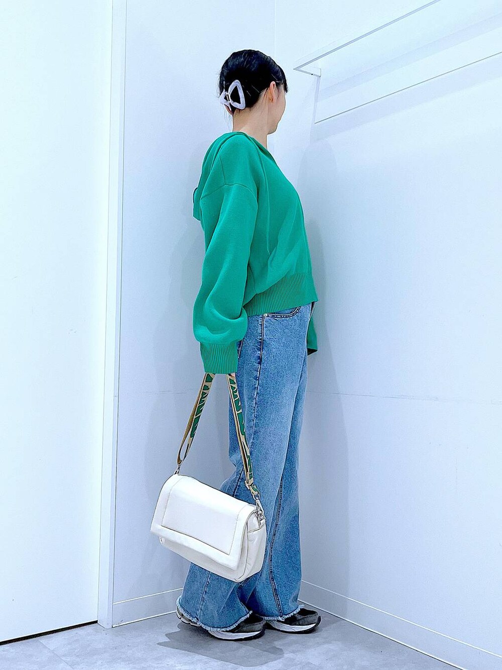 ホワイト系のショルダーバッグ、グリーン系のニット/セーター、ブルー系のデニムパンツを着用したレディースの春コーディネートの4枚目の写真