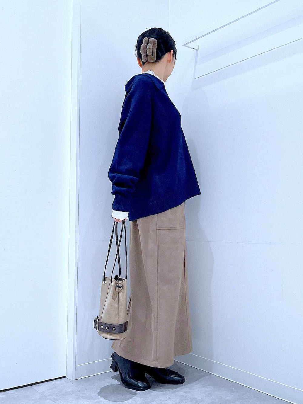 ブラック系のブーツ、ブラウン系のスカート、ベージュ系のハンドバッグを着用したレディースの冬コーディネートの4枚目の写真