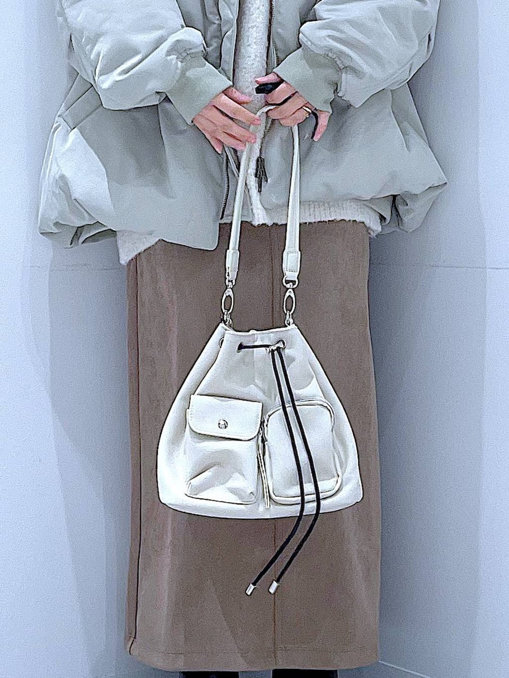 ベージュ系のニット/セーター、ブラック系のブーツ、ブラウン系のスカートを着用したレディースの冬コーディネートの9枚目の写真