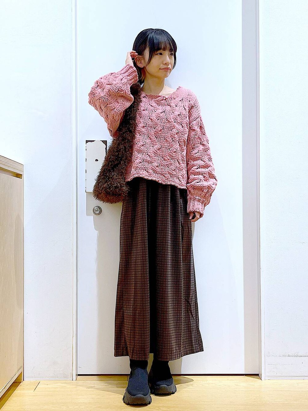 ブラック系のブーツ、ブラウン系のショルダーバッグ、ピンク系のニット/セーターを着用したレディースの冬コーディネートの2枚目の写真