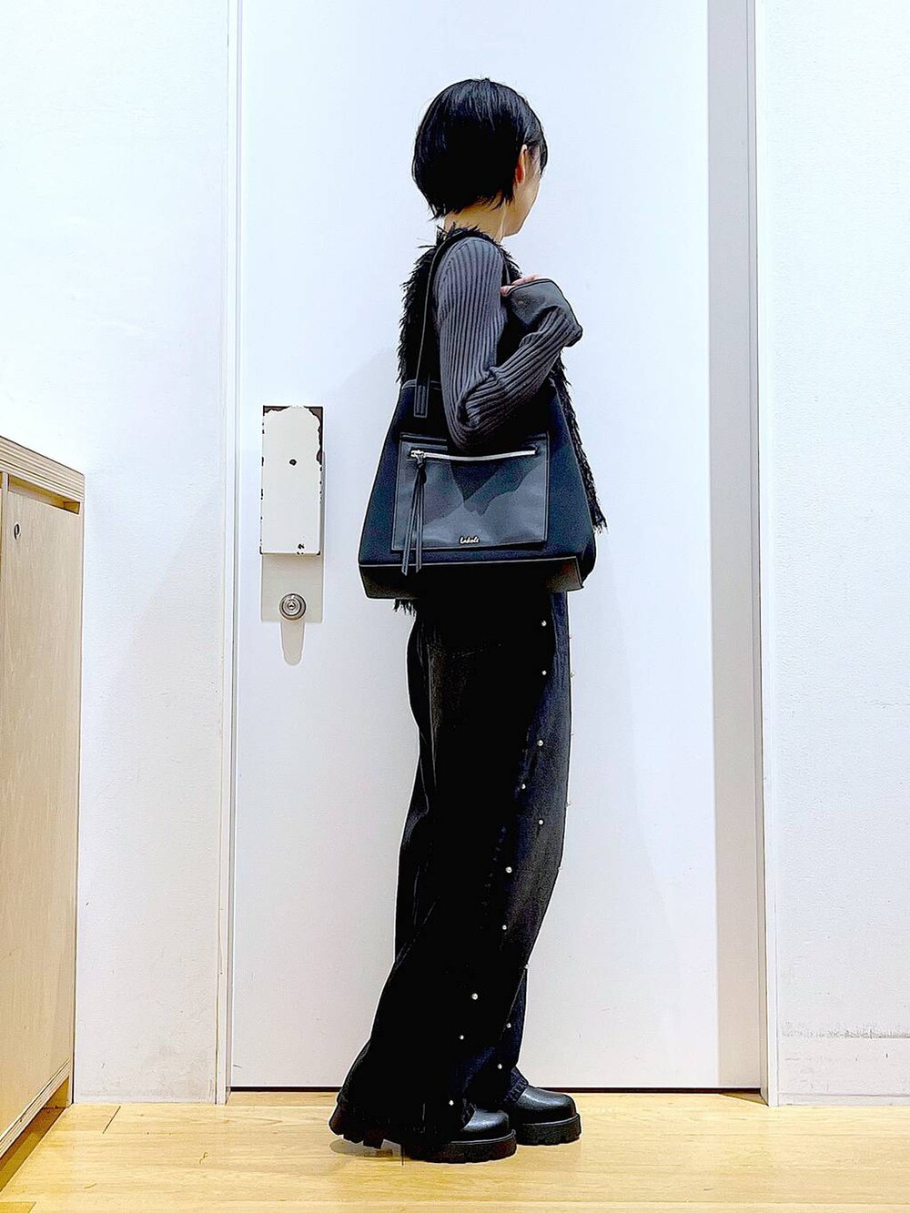 グレー系のニット/セーター、ブラック系のブーツ、ブラック系のトートバッグを着用したレディースの秋コーディネートの4枚目の写真