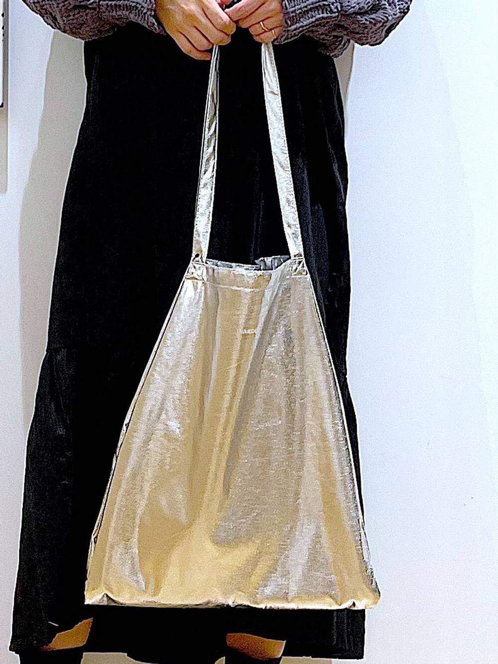 シルバー系のトートバッグ、ブラック系のブーツ、グレー系のニット/セーターを着用したレディースの冬コーディネートの9枚目の写真