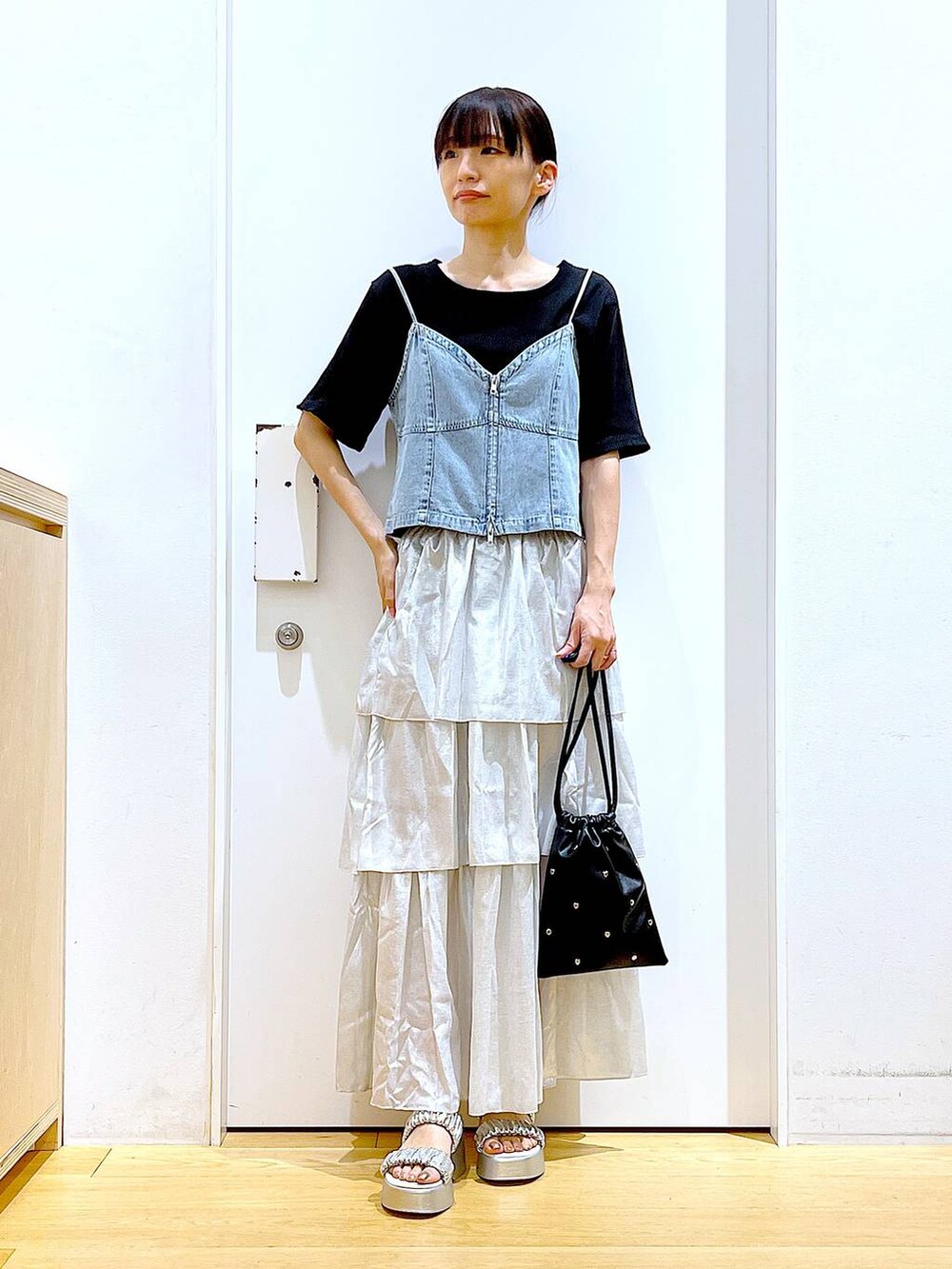 シルバー系のサンダル、ブラック系のショルダーバッグ、ブラック系のTシャツ/カットソーを着用したレディースの夏コーディネートの2枚目の写真