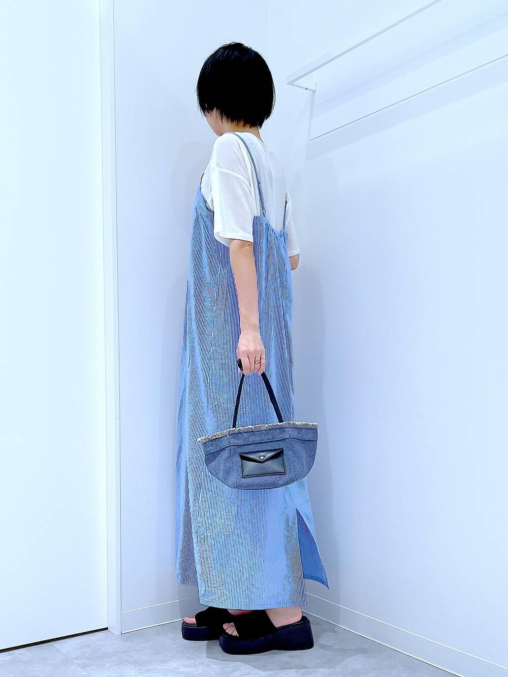 ブルー系のショルダーバッグ、ブラック系のサンダル、ホワイト系のTシャツ/カットソーを着用したレディースの夏コーディネートの3枚目の写真