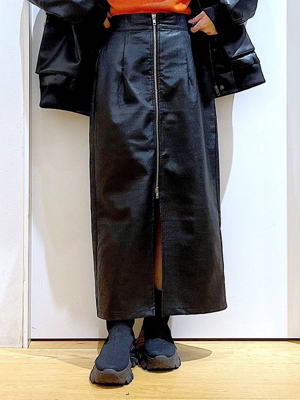 オレンジ系のニット/セーター、ブラウン系のスカート、ブラック系のブーツを着用したレディースの冬コーディネートの8枚目の写真