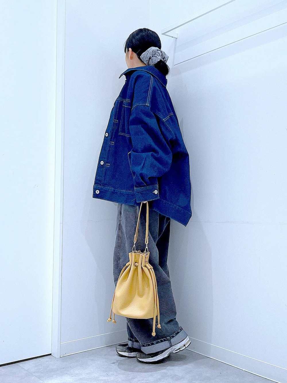 ブルー系のデニムジャケット、ブラック系のデニムパンツ、ブラウン系のショルダーバッグを着用したレディースの春コーディネートの3枚目の写真